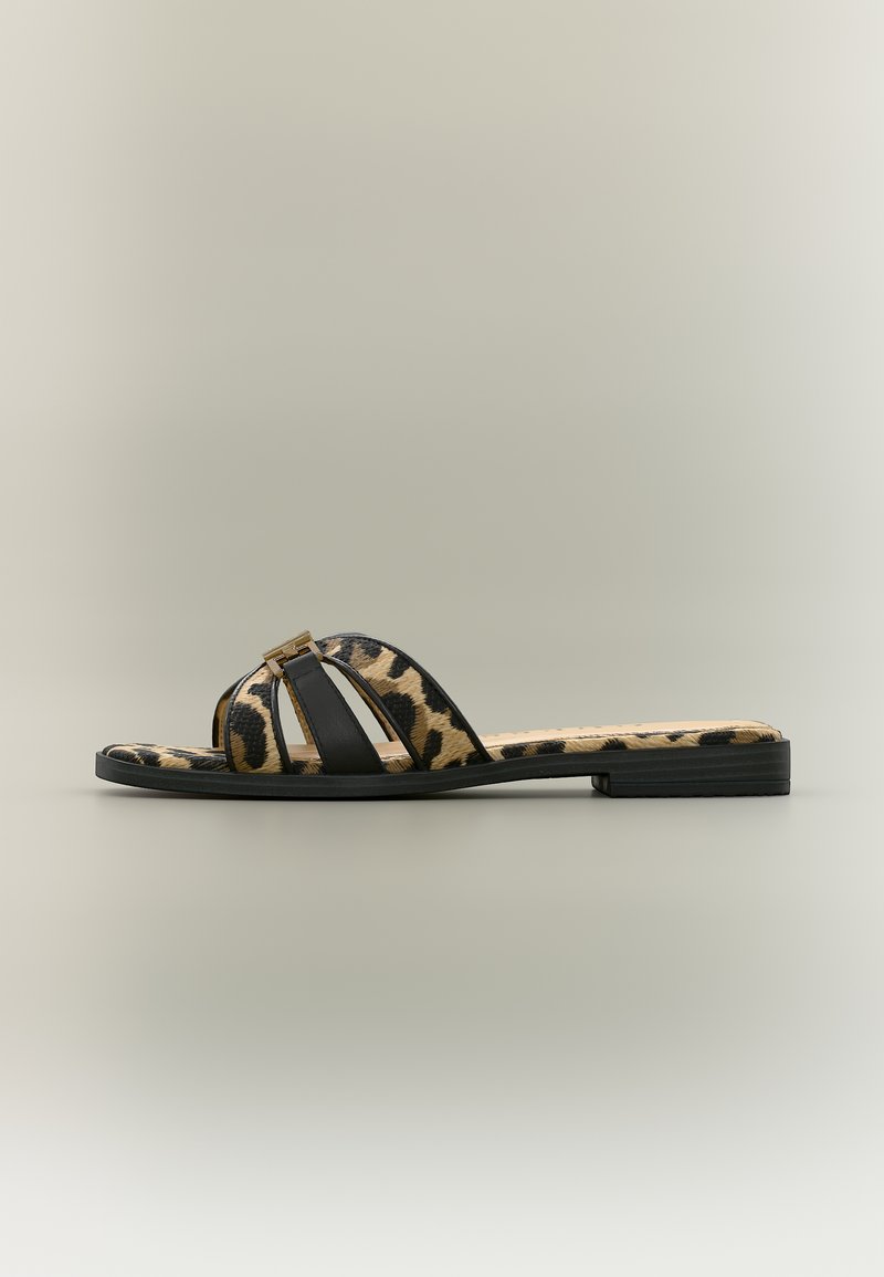 Επίπεδη σανδάλι με λεοπάρ σχέδιο και μαύρα λουράκια που διαθέτουν μια μικρή χρυσή αγκράφα, φωτογραφημένη σε ουδέτερο φόντο.