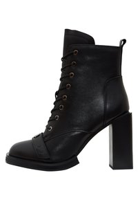 Botín negro de tacón hecho de cuero sintético liso, con cordones en la parte delantera, puntera redondeada y tacón grueso de bloque con un detalle metálico.