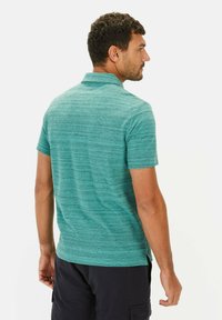 Koszulka polo z krótkim rękawem w kolorze turkusowym z teksturowanym, paskowanym wzorem. Posiada kołnierz oraz boczne rozcięcia na dole dla wygody.