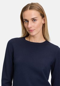 Maglione lavorato a maglia blu navy con collo rotondo e maniche lunghe, caratterizzato da una texture liscia e una silhouette aderente.