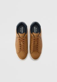 Brown leather sneakers with a textured finish, featuring a rounded toe, white rubber sole, and brown laces. Includes branded insole.