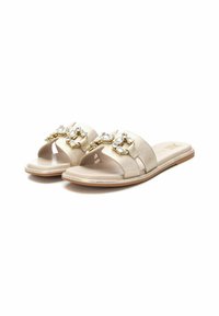 Chanclas deslizantes beige con acabado texturizado, que presentan herrajes en tono dorado y strass transparentes en las correas. Diseño de suela plana.