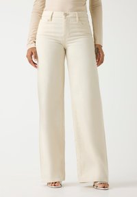 Τζιν με φαρδιά γραμμή και ψηλή μέση σε εκρού ντένιμ. Λείο ύφασμα, ελάχιστες ραφές, κλείσιμο με κουμπιά και τσέπες. Κομψή, ρέουσα σιλουέτα.