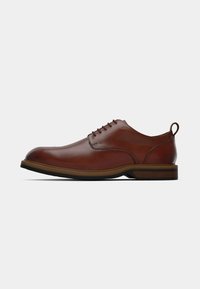 Brown leather lace-up dress shoe with a pull tab at the heel and a layered rubber sole against a white background.