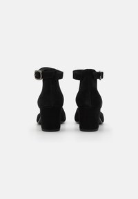 Black suede ankle boots with a square heel and adjustable buckle strap. Features smooth texture and a closed back design.