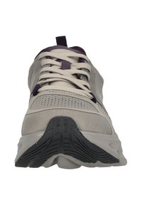 Hellgrauer Sportschuh mit weißen Schnürsenkeln, schwarzem Sohlenprofil und lila Akzenten, von vorne auf einem weißen Hintergrund gesehen.