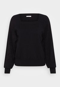 Svart tröja med fyrkantig halsringning, långa ärmar med perforerade detaljer och ribbad nederkant och ärmslut. Mjuk tygstruktur.