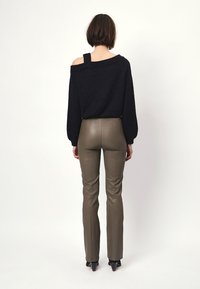 Zwarte off-shoulder trui met lange mouwen, gecombineerd met olijfgroene leren broek die nauwsluitend is, met een gladde textuur en een lichte glans.