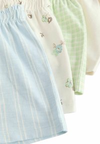 Trois paires de shorts en coton doux. Les couleurs comprennent un bleu clair à rayures, un blanc à imprimé floral et un motif à carreaux verts.