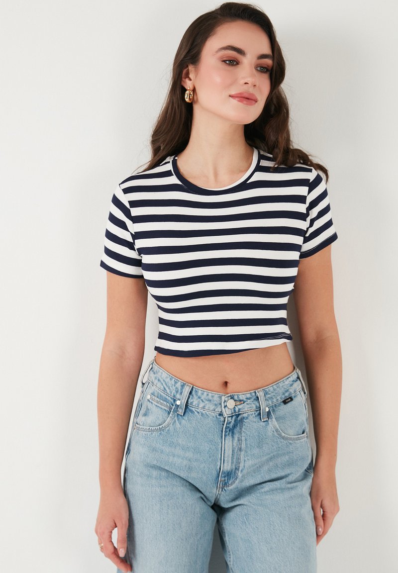 Námořnickě modrý a bílý pruhovaný crop top s kulatým výstřihem a krátkými rukávy, doplněný o světle modré džíny s vysokým pasem.
