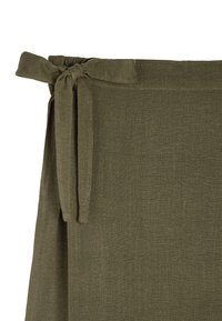 Materiał w oliwkowym kolorze o teksturowanej powierzchni. Posiada wiązanie w talii oraz luźną, zwiewną strukturę dla wygody noszenia.