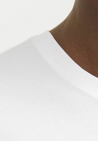 White cotton t-shirt with a seamless crew neck collar, smooth texture, and a close-up view of the neckline and upper chest area.