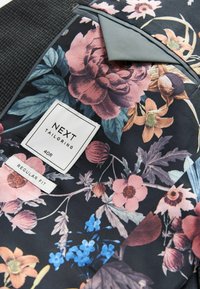 Stof med blomstermønster i pink, blå og grønne blomster på sort baggrund. Indeholder "NEXT TAILORING" mærke, størrelse 40R, og "REGULAR FIT."