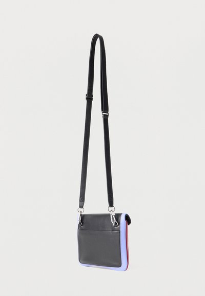 Μικρή ορθογώνια δερμάτινη τσάντα crossbody σε μαύρο με μοβ άκρες και ρυθμιζόμενο μαύρο λουρί, κρεμασμένη μπροστά σε λευκό φόντο.