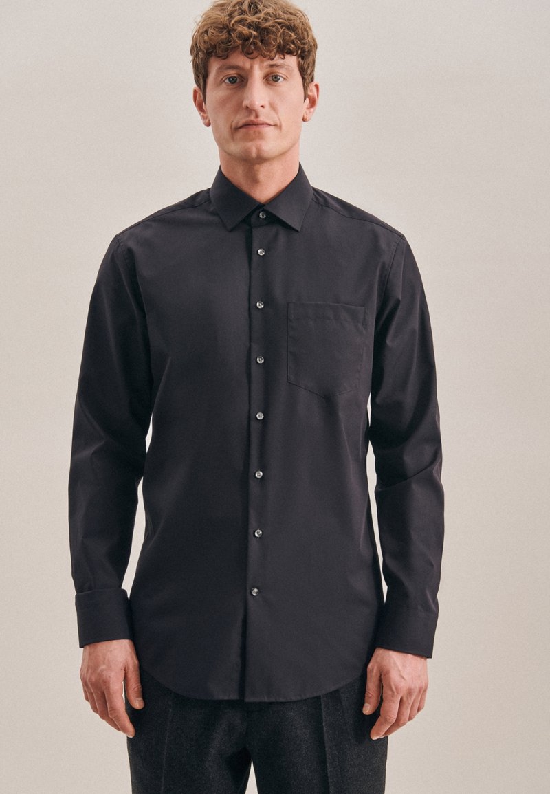 Zwarte langarmshirt van een zachte stof, met een spitsel kraag, knoopsluiting aan de voorkant, een enkele borstzak en een subtiele glans.