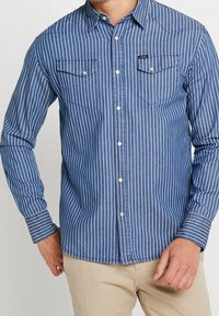 Blauw-wit gestreept overhemd met lange mouwen, knoopsluiting aan de voorkant, twee borstzakken en een puntige kraag. Zachte, gestructureerde stof.