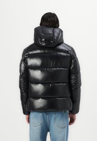Black puffer jacket with a glossy finish, featuring a hood, horizontal quilted sections, and a snug fit. Ideal for warmth and comfort.