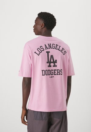 Camiseta de algodón de color rosa claro con cuello redondo, mangas cortas y texto impreso en negro: "LOS ÁNGELES," "LA," y "DODGERS" en la parte posterior.