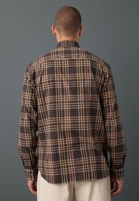 Camicia a quadri in marrone e beige con polsini a bottoni, colletto appuntito e vestibilità regolare. Tessuto morbido e design strutturato.