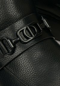 Černá kožená bota s texturovaným povrchem, širokým páskem s charakteristickým černým kovovým sponou a hladkými konturami.