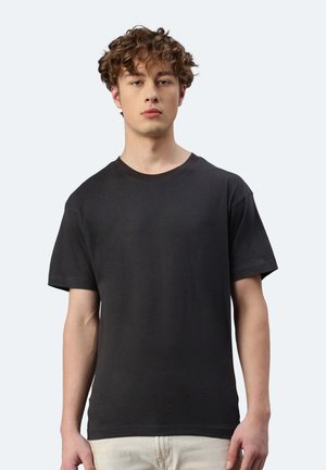 T-shirt nera a maniche corte in cotone, con scollatura rotonda e vestibilità relaxed, esposta su uno sfondo neutro.
