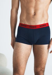 Námořnické boxerky s červeným elastickým páskem s logem "HUGO". Hladká tkanina, přiléhavý střih a střední výška pro pohodlí.