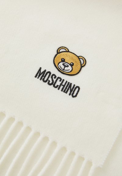 Sciarpa bianca con un design di un orso ricamato in marrone e nero, con la parola "MOSCHINO" sottostante. I bordi presentano un dettaglio frangiato.