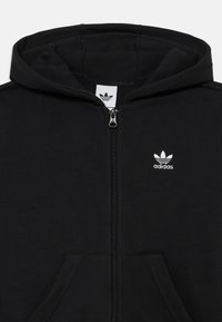 Fekete cipzáros kapucnis pulóver, puha anyagból készült, kapucnival, elülső zsebekkel és egy kis fehér Adidas logóval a mellkasán.