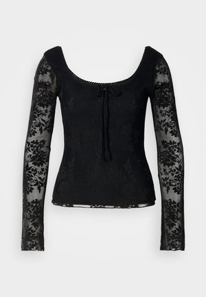 Svart langermet topp med blomstermønstret blonder, scoop-hals, og en knytedetalj foran. Halvgjennomsiktige ermer gir tekstur.
