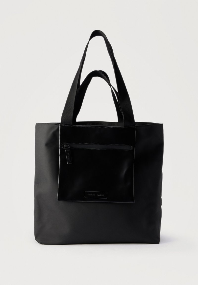 Μαύρη τσάντα ώμου με εμπρόσθια τσέπη με φερμουάρ και διπλές λαβές, τοποθετημένη πάνω σε απλό φωτεινό φόντο.