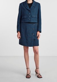 Modrý kostkovaný set sak a sukně, zkrácený design, dvouřadové knoflíky, hladká textura, spárovaný s černými páskovými podpatky.