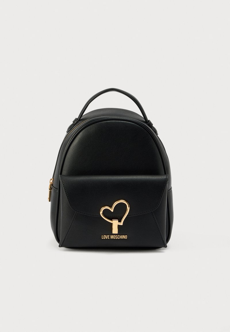 Μαύρο σακίδιο από συνθετικό δέρμα με στρογγυλεμένο σχήμα, μπροστινή τσέπη με καπάκι, χρυσά μεταλλικά στοιχεία σε σχήμα καρδιάς και λογότυπο της μάρκας στο κάτω μέρος.