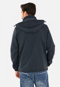 Giacca con cappuccio blu navy dotata di colletto testurizzato, polsini elasticizzati e vita con cordino; realizzata in materiale leggero e resistente all'acqua.
