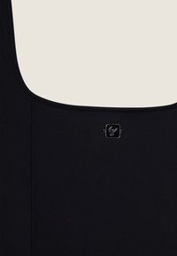 Musta uimapuku saumattomalla suunnittelulla, jossa on neliön muotoinen logotieto ja saumattomat reunat sileän viimeistelyn saavuttamiseksi.