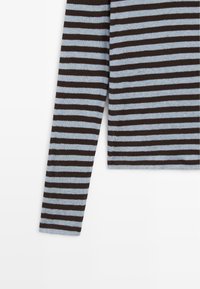 Striped long-sleeve shirt in light blue and dark brown, made of soft fabric with a fitted shape and a clean neckline.