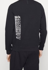 Černá mikina s dlouhými rukávy, na zadní straně s bílým grafickým potiskem. Vyrobena z hladké, elastické tkaniny.