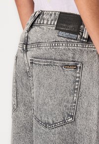 Jeans din denim gri cu un finisaj texturat, design cu cinci buzunare și o etichetă din piele neagră pe talie cu marcajul brandului.
