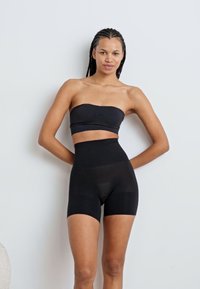 Top negru fără bretele, cu pantaloni scurți asortați, cu talie înaltă, realizat dintr-un material neted și elastic, având un design ajustat și cusături minime.