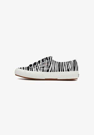 Des baskets en toile avec un motif rayé zebra noir et blanc, une semelle en caoutchouc blanche et des œillets noirs. Accent texturé blanc sur les côtés.