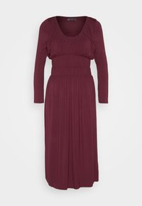 Μπορντό φόρεμα με μακριά μανίκια, στρογγυλή λαιμόκοψη, πτυχωτό μπούστο και πλισέ φούστα. Φτιαγμένο από μαλακό, υφασμάτινο υλικό.