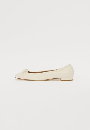 Ballet flat couleur crème avec une finition en cuir lisse, bout rond et petit nœud à l'avant, doté d'un petit talon plat.