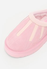Rosa slip-on sko gjord av mocka och syntetiskt material. Har kontrasterande ljusrosa detaljer och sömmar, med en texturerad sula.