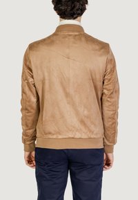 Chaqueta bomber de ante marrón con cuello y puños acanalados, que presenta una textura suave y un diseño minimalista, vista desde la parte posterior.