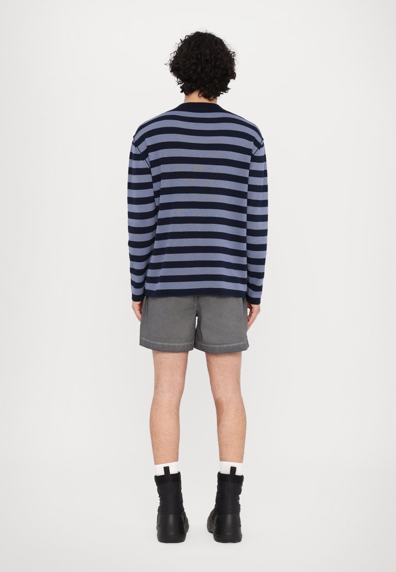 Navy and light blue striped long-sleeve shirt, paired with gray shorts. Featured with solid black ankle boots.