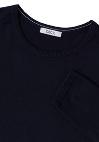 Pull en maille bleu marine foncé avec col rond et manches longues, doté d'une étiquette blanche avec le nom de la marque "CECIL" à l'intérieur du col.