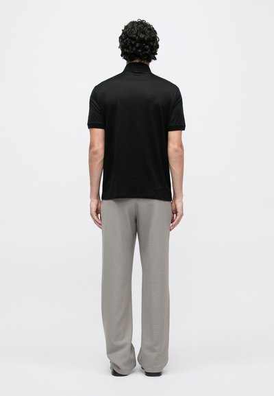 Melna īsroku polo krekls, kombinēts ar pelēkām platām bikšu kājām. Minimālistisks dizains, gluda tekstūra un pieguļošs siluets.