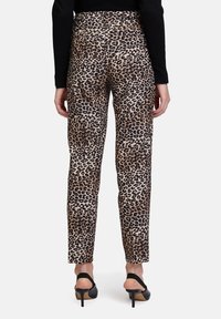 Pantalones de leopardo con un diseño ajustado, cintura alta y textura suave, combinados con tacones negros de punta abierta.