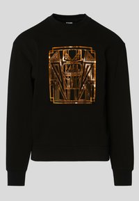 Felpa nera con scollo tondo e maniche lunghe. Presenta un logo geometrico metallico dorato sul davanti, tessuto di cotone testurizzato.