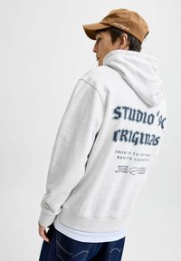 Sudadera gris claro con un gran estampado gráfico en la parte posterior, que presenta texto azul. Material de mezcla de algodón con un bolsillo canguro y puños acanalados.