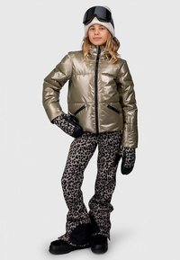 Síruha, mely egy fémes olívazöld puffert kabátot, leopárdmintás nadrágot, fekete kesztyűket, szürke sapkát és síalátét szemüveget tartalmaz.